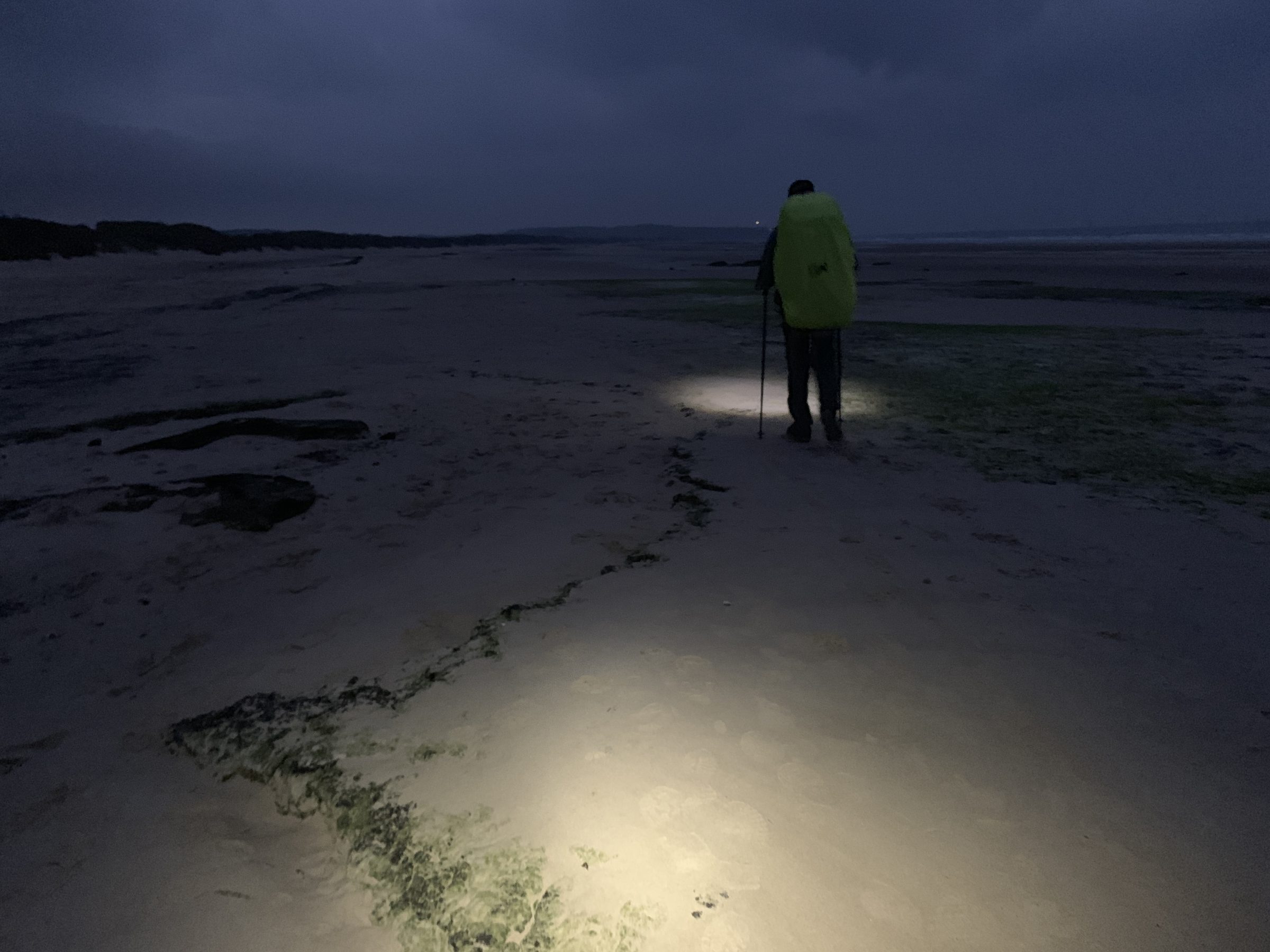 Randonneur avec lampe frontale sur une plage de nuit