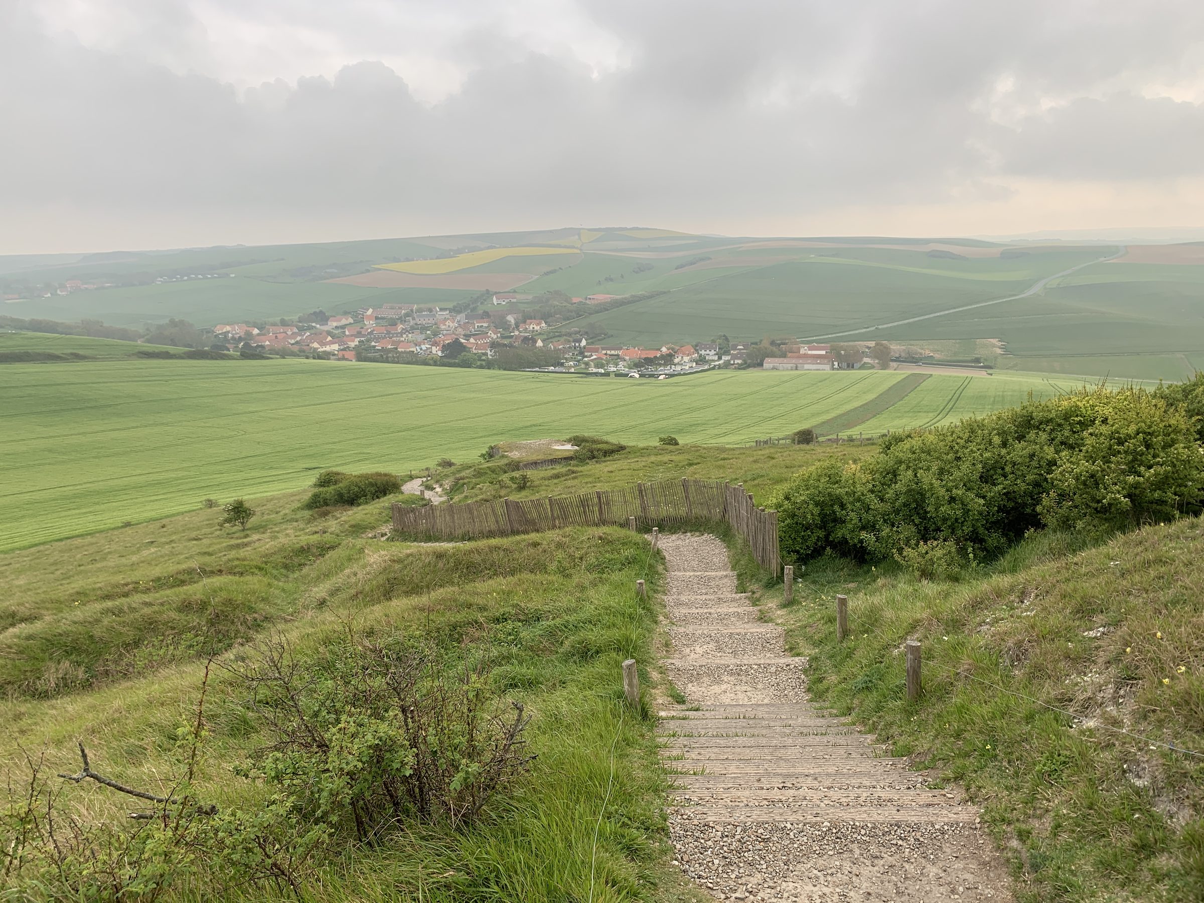 Sentier avec escalier descendant vers un village de campagne